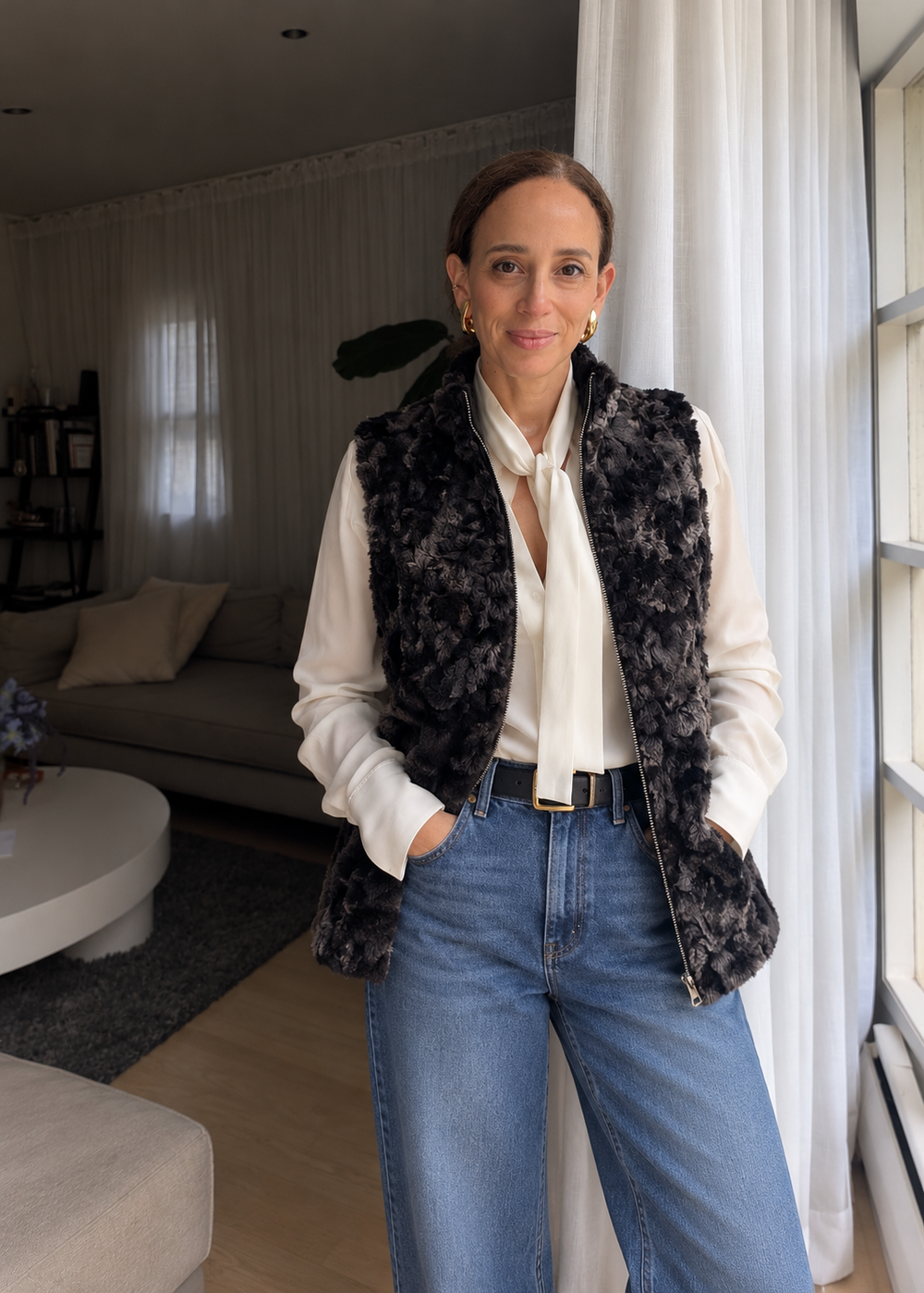 The Bern Vest in Chinchilla over an ivory tie-neck blouse, with jeans