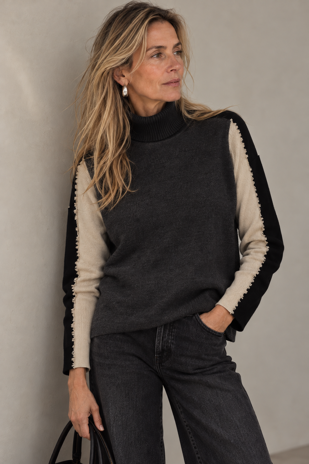 The Riga top, a charcoal turtleneck with contrast sleeves, worn with black wide-leg denim