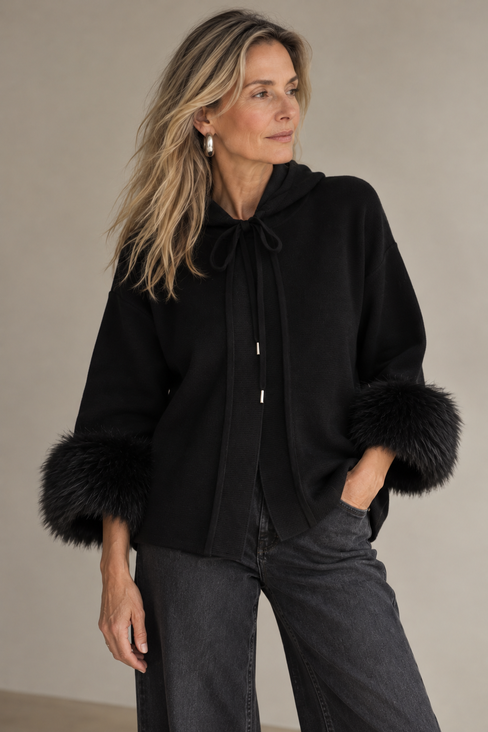 The Hampstead Hoodie in black with fur cuffs, worn with black wide-leg denim