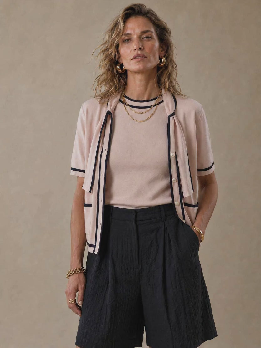 The Genoa women's short-sleeve cotton knit cardigan featuring a romantic tie-neck collar, contrast piping, and two front patch pockets.
