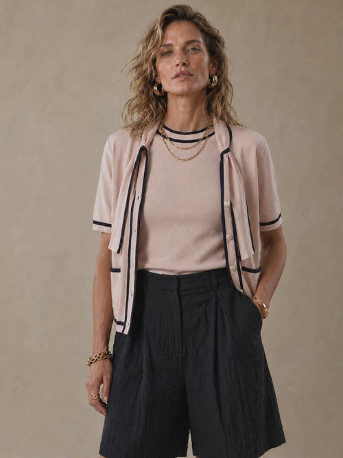 The Genoa women's short-sleeve cotton knit cardigan featuring a romantic tie-neck collar, contrast piping, and two front patch pockets.