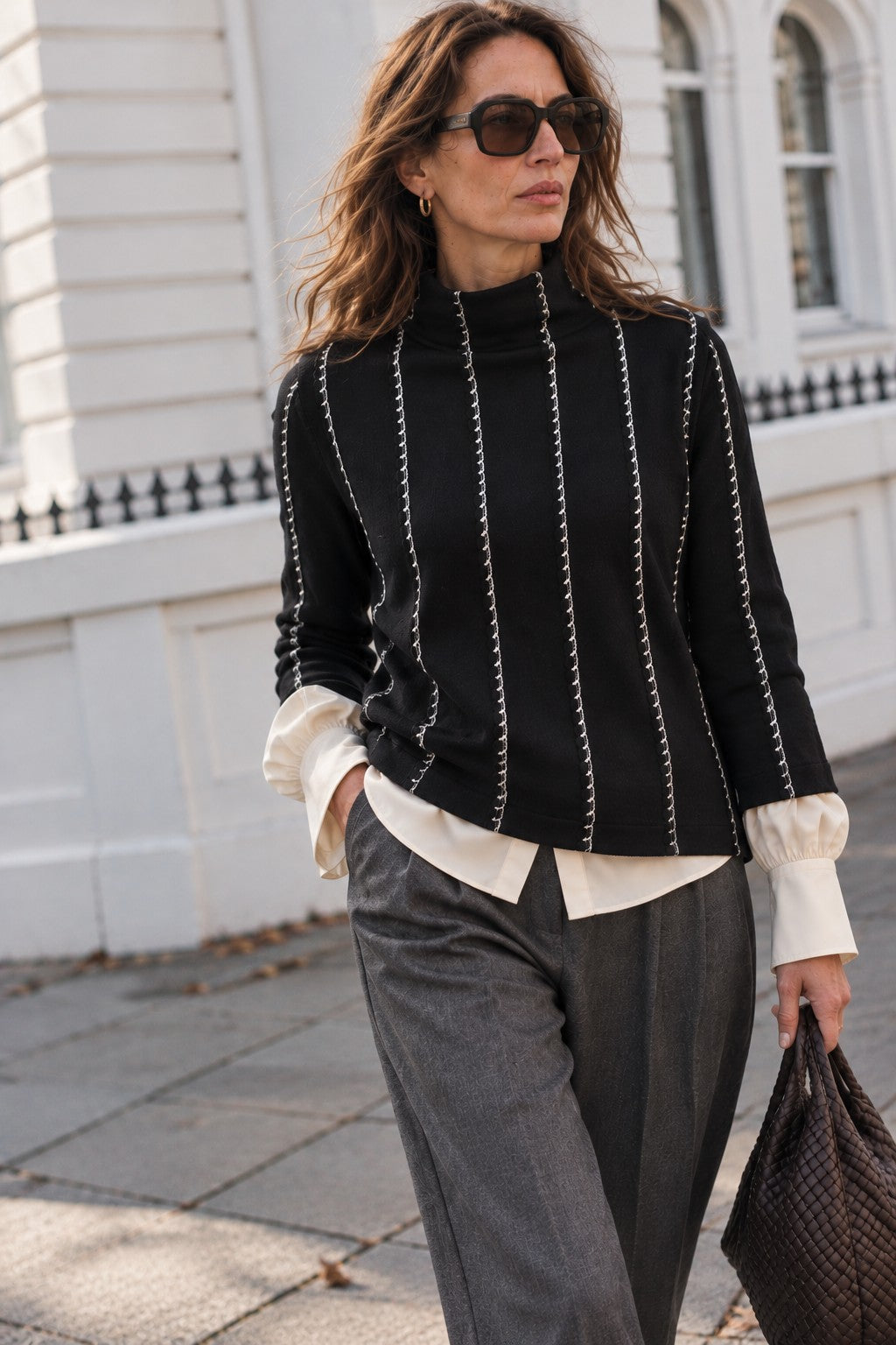 The Nicosia Turtleneck in black and ivory, worn over a silk shirt